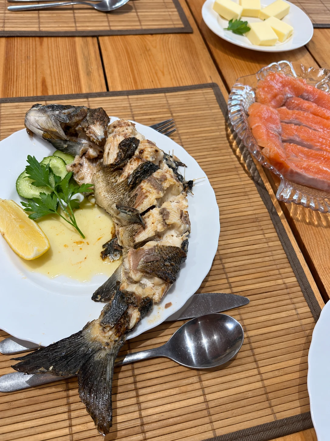 Приготовленная рыба с лимоном и зеленью, нарезанная рыба и масло на деревянном столе